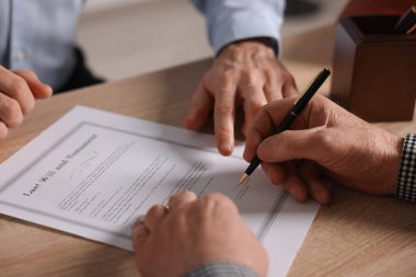 Noter, son vasiyet ve vasiyetnamenin nerede imzalanacağını gösteriyor. Ofisteki ahşap masada, yakın plan.