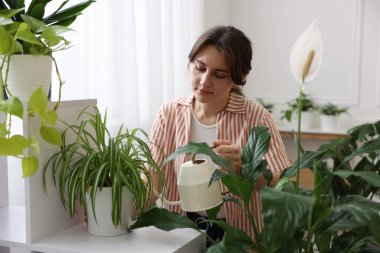 Evdeki çiçekleri sulayan güzel bir kadın.