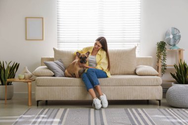 Evdeki kanepede tatlı köpeğiyle dinlenen bir kadın.