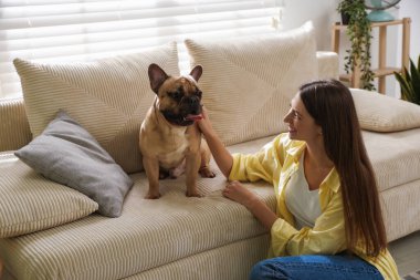 Evdeki kanepenin yanında tatlı köpeği olan bir kadın.