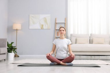 Hamile kadın evde yoga yapıyor.