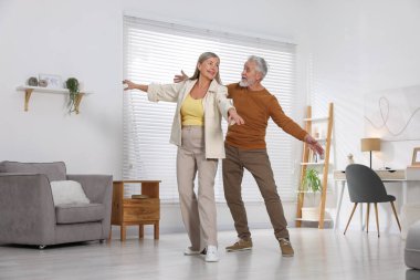 Mutlu yaşlı çift evde dans ediyor.