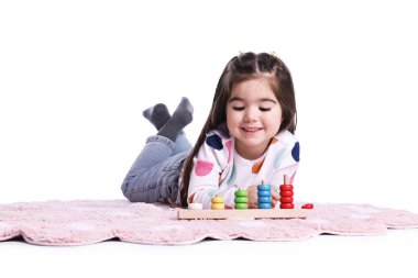 Beyaz arka planda istifleme ve sayma oyunlarıyla oynayan sevimli küçük kız.