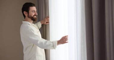 Evde şık pencere perdeleri açan adam