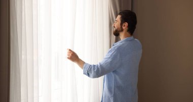 Evde şık pencere perdeleri açan adam