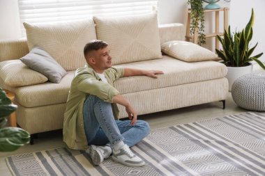 Evdeki kanepenin yanında dinlenen genç adam, mesaj için yer var.