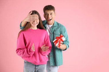 Sevgililer Günü. Mutlu genç adam pembe arka planda kız arkadaşına sürpriz yapıyor, mesaj için yer var.