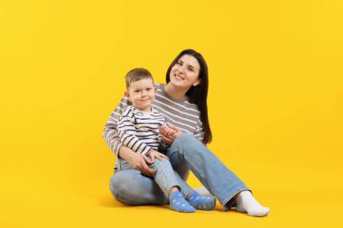 Mutlu anne sarı arka planda oğluna sarılıyor.