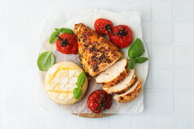 Lezzetli kızarmış tavuk göğsü, peynir, güneşte kurutulmuş domates ve fesleğen beyaz fayanslı masa, üst manzara
