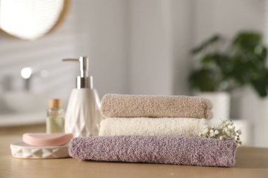 Temiz havlu yığını, çingene çiçekleri ve kozmetik ürünleri kapalı masa, yakın plan.