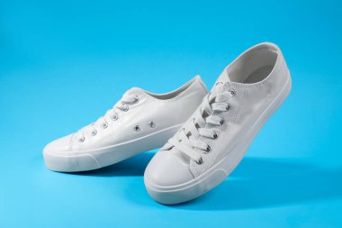 Açık mavi arka planda şık bir çift spor ayakkabı, yakın plan.