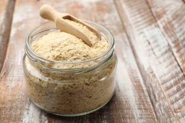 Cam kavanozda kuru maya taneleri ve ahşap masada kepçe, yakın plan. Metin için boşluk