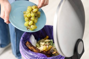 Mutfaktaki çöp tenekesine üzüm atan kadın, yakın plan.