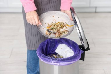 Mutfaktaki çöp tenekesine yemek atan kadın, yakın plan.