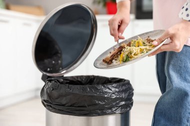 Mutfaktaki çöp tenekesine yemek atan kadın, yakın plan.