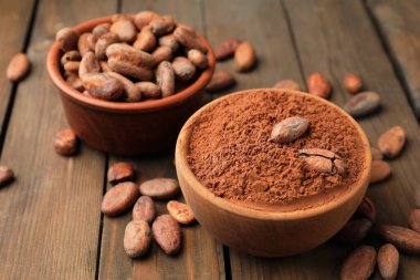 Doğal kakao çekirdeği ve toz tahta masanın üzerinde, yakın plan.