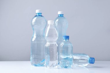 Beyaz masada gri arka planda farklı boyutlarda su şişeleri