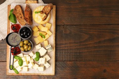 Farklı peynir, zeytin, ekmek, yağ ve fesleğen içeren servis masası, üst manzara. Metin için boşluk