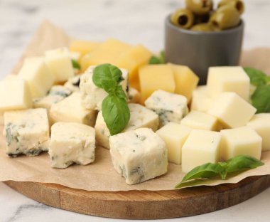 Açık mermer masada değişik peynir, zeytin ve fesleğen içeren servis panosu, yakın plan.