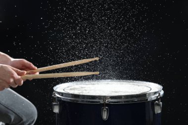 Siyah arkaplanda davul çalan bagetli adam, yakın plan