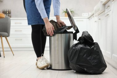 Mutfaktaki çöp kutusuna plastik poşet koyan kadın, yakın plan.