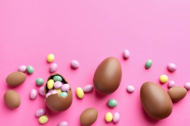 Pembe arka planda şekerli, çikolatalı Paskalya yumurtaları. Metin için boşluk