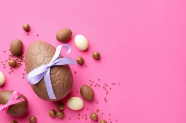 Pembe arka planda şekerli, çikolatalı Paskalya yumurtaları. Metin için boşluk