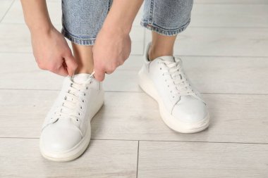 Beyaz spor ayakkabı bağcığı bağlayan kadın, yakın plan.