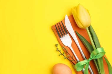 Paskalya kutlaması. Çiçekli masa dekoru ve sarı arka planda boyanmış yumurta, düz yatak. Metin için boşluk