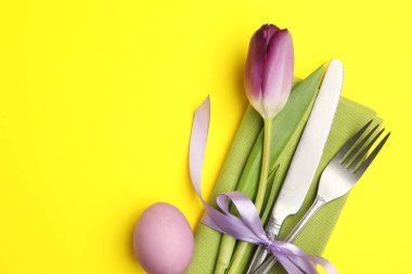 Paskalya kutlaması. Çiçekli masa dekoru ve sarı arka planda boyanmış yumurta, düz yatak. Metin için boşluk