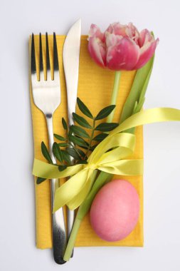 Paskalya sofrası. Beyaz arka planda lale ve boyalı yumurta ile güzel gümüş takımlar, üst manzara.