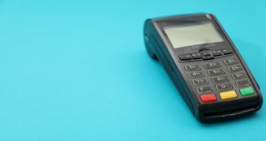 Açık mavi arka planda bir ödeme terminali, yakın plan. Metin için boşluk