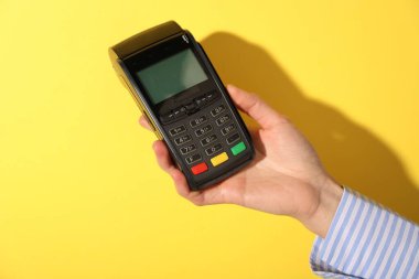 Sarı arka planda ödeme terminali olan kadın, yakın plan.