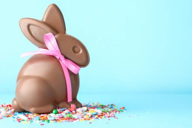Çikolatalı Paskalya tavşanı ve açık mavi arka planda serpiştirilmiş çikolata. Metin için boşluk