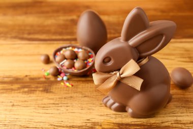 Çikolatalı Paskalya tavşanı, şekerli yumurtalar ve ahşap masaya serpiştirilmiş şekerler, yakın plan.
