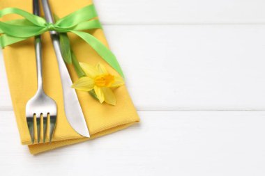 Paskalya sofrası. Beyaz ahşap arka planda nergis çiçeği olan güzel gümüş takımlar, yakın plan. Metin için boşluk