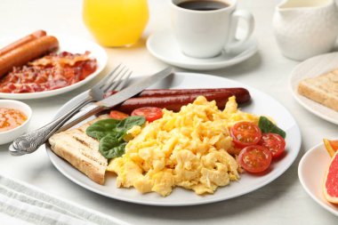 Lezzetli bir kahvaltı. Sosis ve domatesli nefis çırpılmış yumurta. Masada servis ediliyor. Yakın plan.