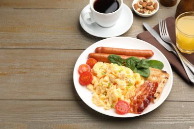 Lezzetli bir kahvaltı. Pastırmalı omlet, sosis ve domatesler ahşap masada servis ediliyor. Yakın plan. Metin için boşluk
