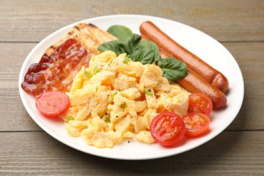 Lezzetli bir kahvaltı. Pastırmalı yumurta, sosis ve domatesler ahşap masada, yakın plan.