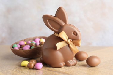 Çikolatalı Paskalya tavşanı ve yumurta ahşap masada açık gri arka planda, yakın plan.