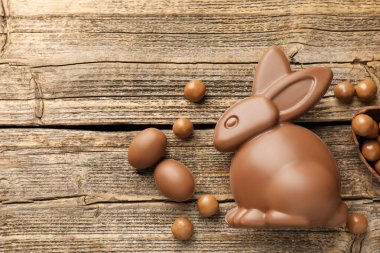 Çikolatalı Paskalya tavşanı ve yumurtalar ahşap masada, düz yatıyordu. Metin için boşluk