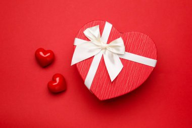 Saint Valentine's day. Beautiful heart shaped gift and decorative hearts on red background, flat lay