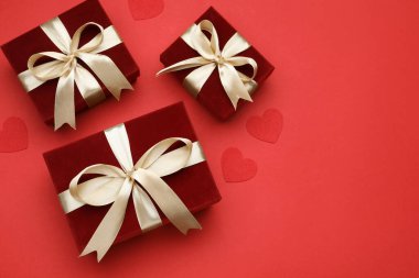 Sevgililer Günü. Güzel hediyeler ve kırmızı arka planda dekoratif kalpler, düz yatış. Metin için boşluk