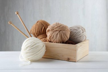 Örgü iplikleri ve iğneler beyaz ahşap masada kutunun içinde.