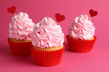 Sevgililer Günün kutlu olsun. Pembe arka planda kırmızı kalp kaplamalı lezzetli kekler, yakın plan.