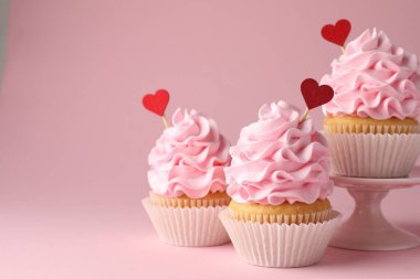 Sevgililer Günün kutlu olsun. Pembe arka planda kırmızı kalp kaplamalı lezzetli kekler, yakın plan. Metin için boşluk