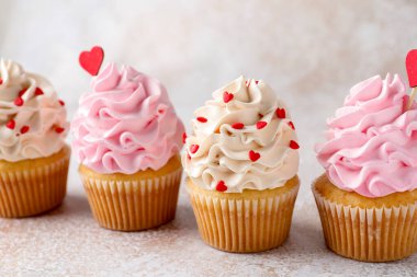 Sevgililer Günün kutlu olsun. Gri masada kırmızı kalpli lezzetli kekler, yakın plan.