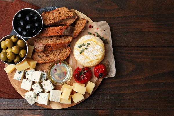 Farklı peynir türleri, zeytin ve diğer atıştırmalıklar ahşap masa, üst manzara. Metin için boşluk