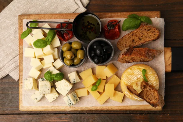 Tahtada değişik peynir, zeytin, ekmek, yağ ve fesleğen var.