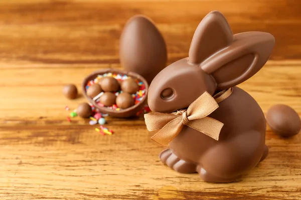 Çikolatalı Paskalya tavşanı, şekerli yumurtalar ve ahşap masaya serpiştirilmiş şekerler, yakın plan.
